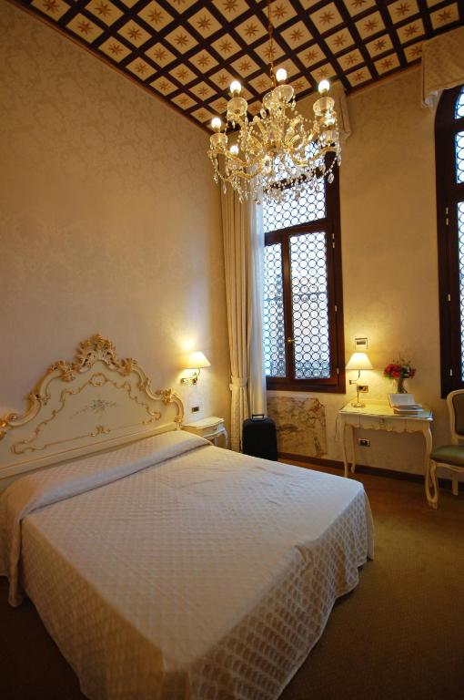 a bedroom with a large white bed with a chandelier at Hotel Torino in Venice