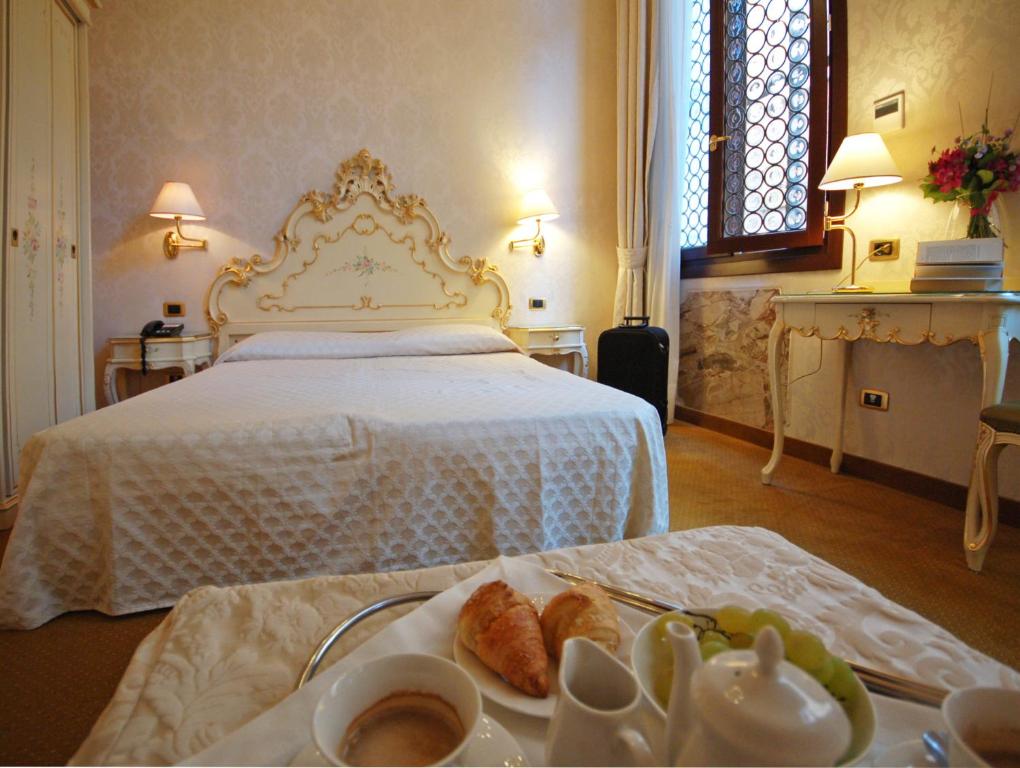 a hotel room with a bed with a tray of food at Hotel Torino in Venice