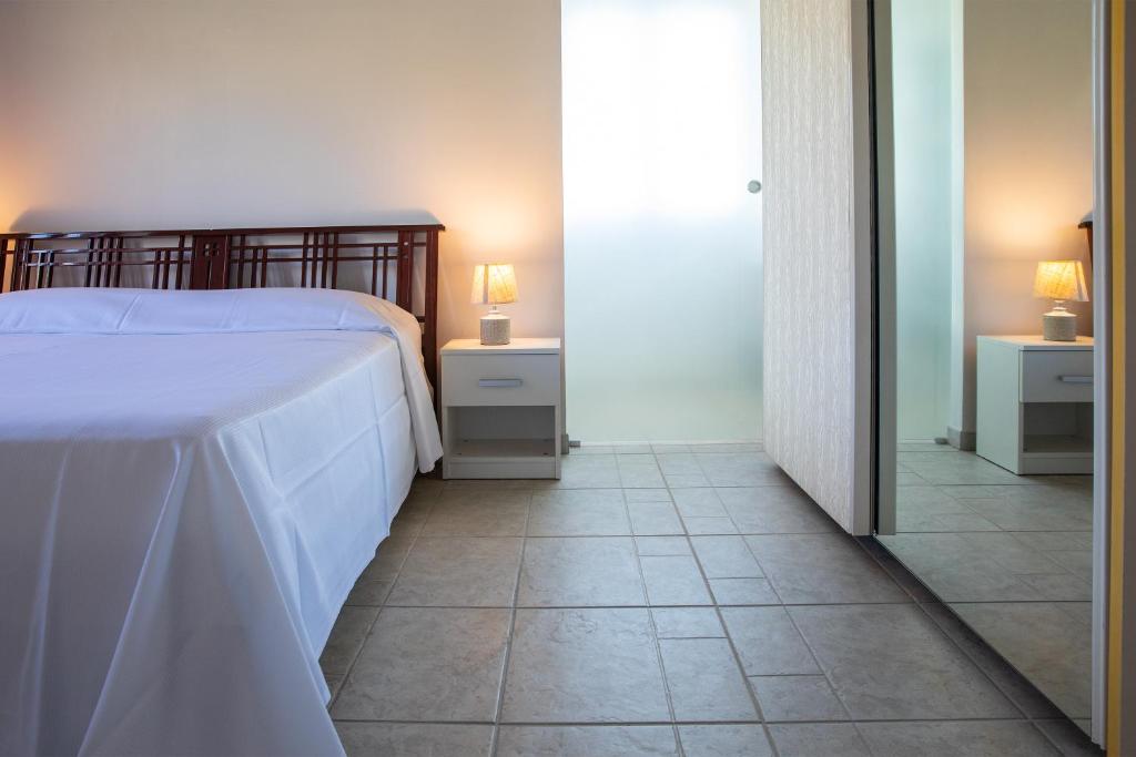 een slaapkamer met een bed en een tegelvloer bij Casale Manca - Luxury Country House - The quiet with a sea view in Licata