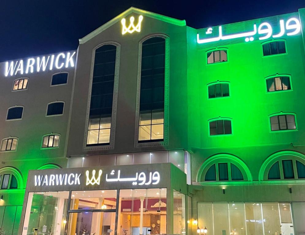 a green building with a sign on the side of it at Warwick Al Jubail Hotel in Al Jubail