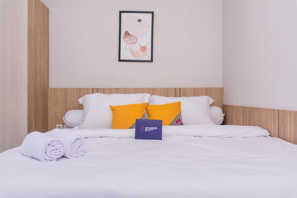 1 cama con sábanas blancas y almohadas amarillas en Singgahsini Rungkut Syariah, en Medokanayu