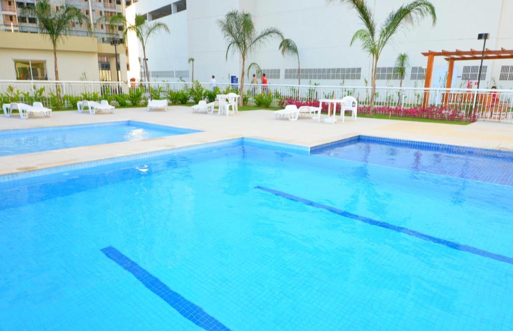 a large blue swimming pool with white chairs and palm trees at Rio Parque in Rio de Janeiro