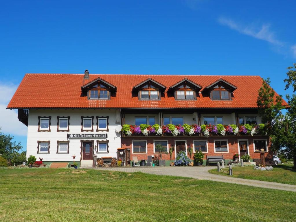 un grand bâtiment blanc avec un toit orange dans l'établissement Gästehaus Fechtig, à Hergensweiler