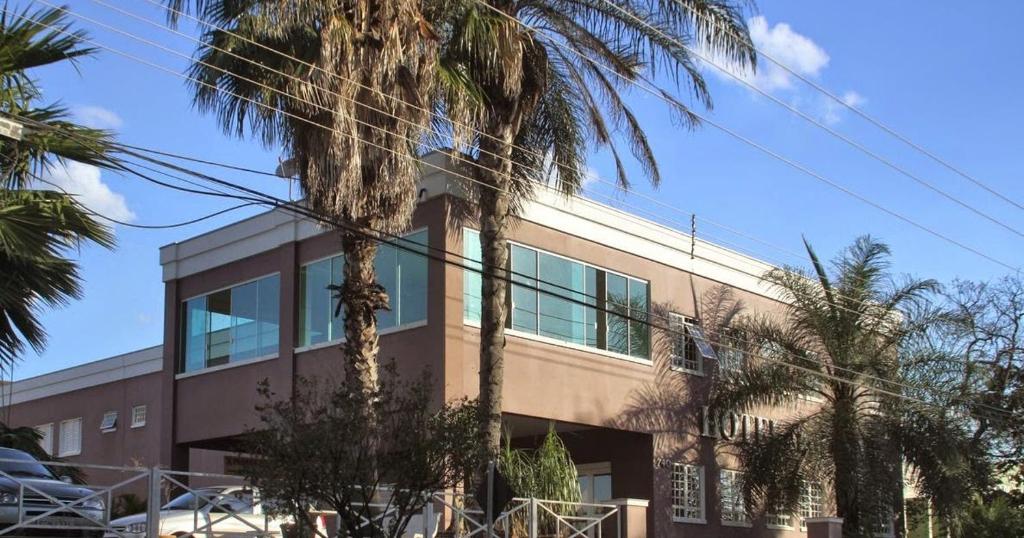 Un edificio con palmeras delante. en Hotel Expoflora, en Cosmópolis