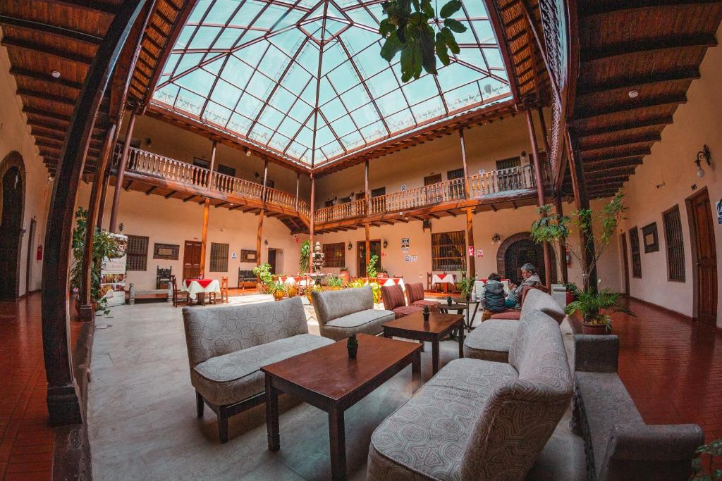 Hotel Cajamarca في كاخاماركا: غرفة كبيرة بها كنب وطاولات وسقف زجاجي