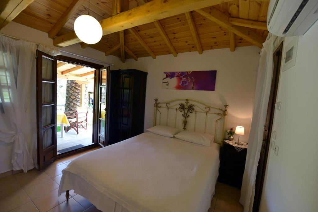 a bedroom with a white bed and a patio at Haus Katerina in Vourvourou