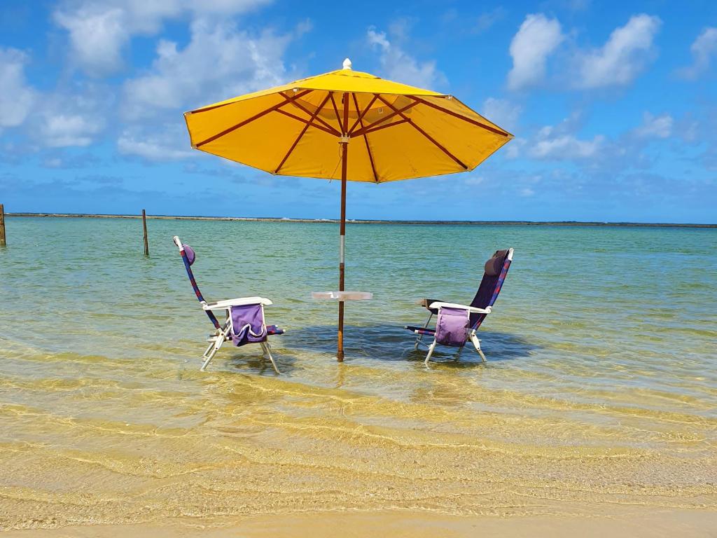 - deux chaises et un parasol sur la plage dans l'établissement Condominio Nui Supreme - By Maya - Muro Alto - Porto de Galinhas, à Porto de Galinhas