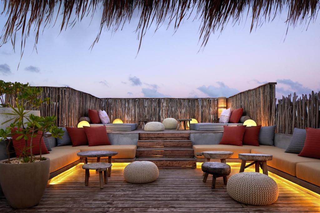 - une terrasse avec un canapé, des tables et des chaises dans l'établissement Kimpton Aluna Resort Tulum, an IHG Hotel, à Tulum