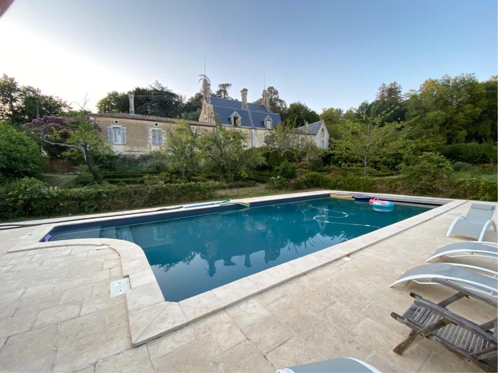 a swimming pool with chairs and a house in the background at Château du Roc in Saint-Thomas-de-Cônac