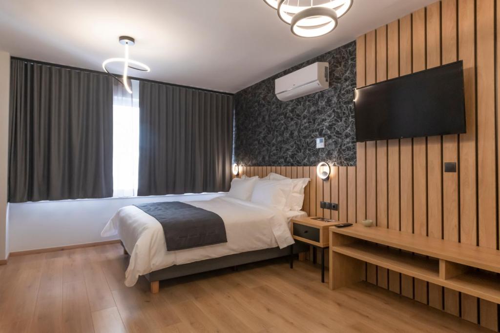 een slaapkamer met een bed, een bureau en een televisie bij Ethereal Athεns in Athene