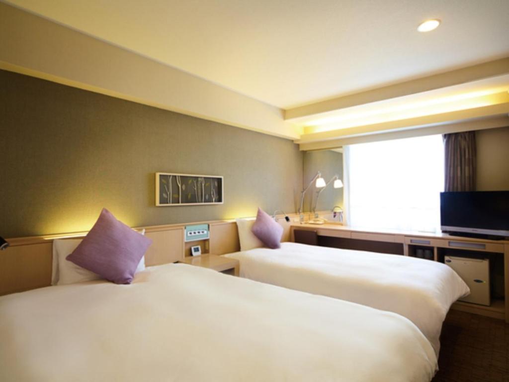 - 2 lits dans une chambre d'hôtel avec des oreillers violets dans l'établissement Tmark City Hotel Sapporo - Vacation STAY 90450v, à Sapporo