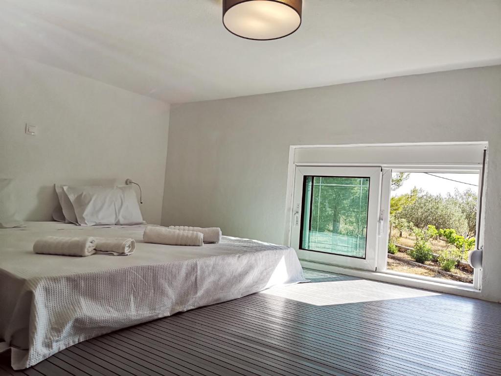 a white bedroom with a large bed and a window at Chrysanthi Villa, Living in Nature in vlicha
