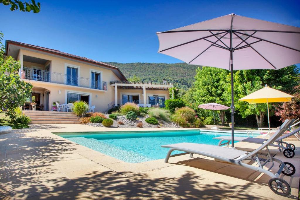 uma casa com uma piscina com uma cadeira e um guarda-sol em Le Mas de Sevrier em Sévrier