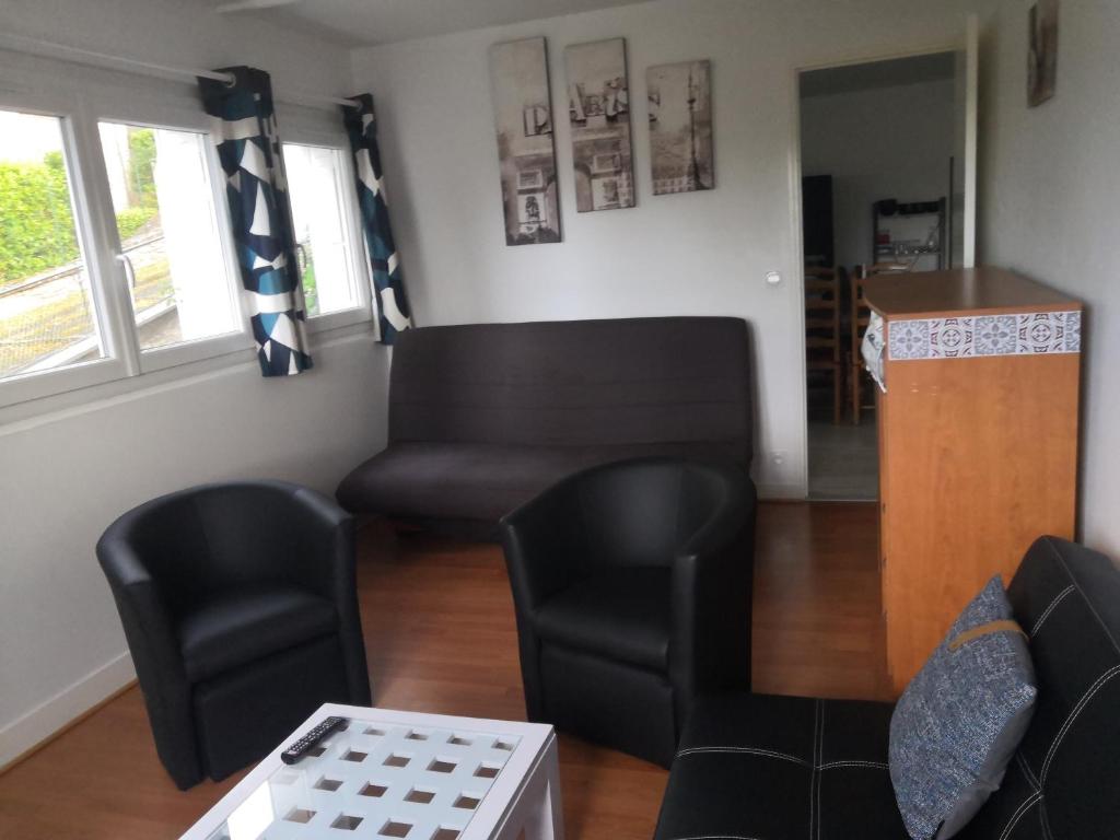 a living room with black chairs and a couch at Logement neuf en face de la forêt. Accès cour. in Bagnoles de l&#39;Orne