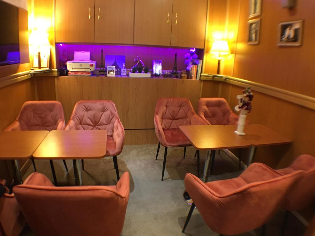 une salle d'attente avec des tables, des chaises et des lumières violettes dans l'établissement Le Nouvel Hôtel du Théâtre, à Paris