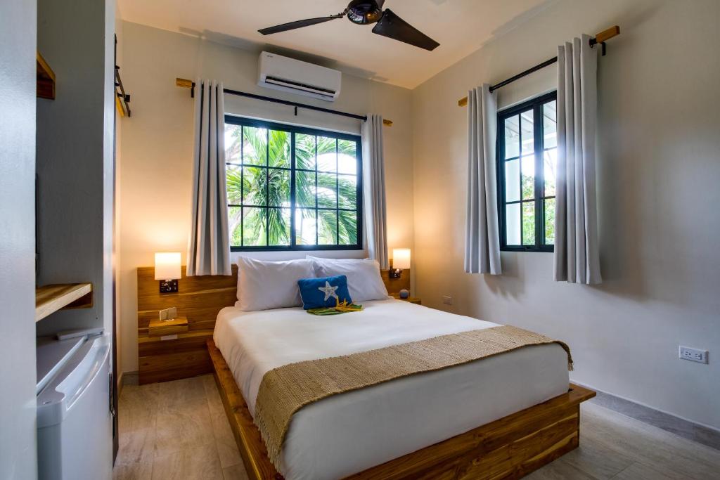 a bedroom with a large bed with two windows at The Sea Glass Inn in Placencia Village