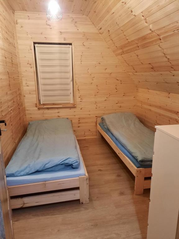 a bedroom with two beds in a wooden cabin at Mazurska Sielanka in Orzysz