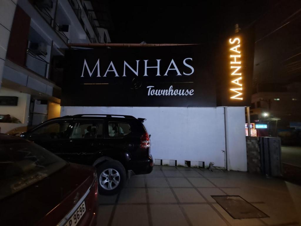 a car parked in front of a store with a sign at Manhas Townhose in Tripunnittara