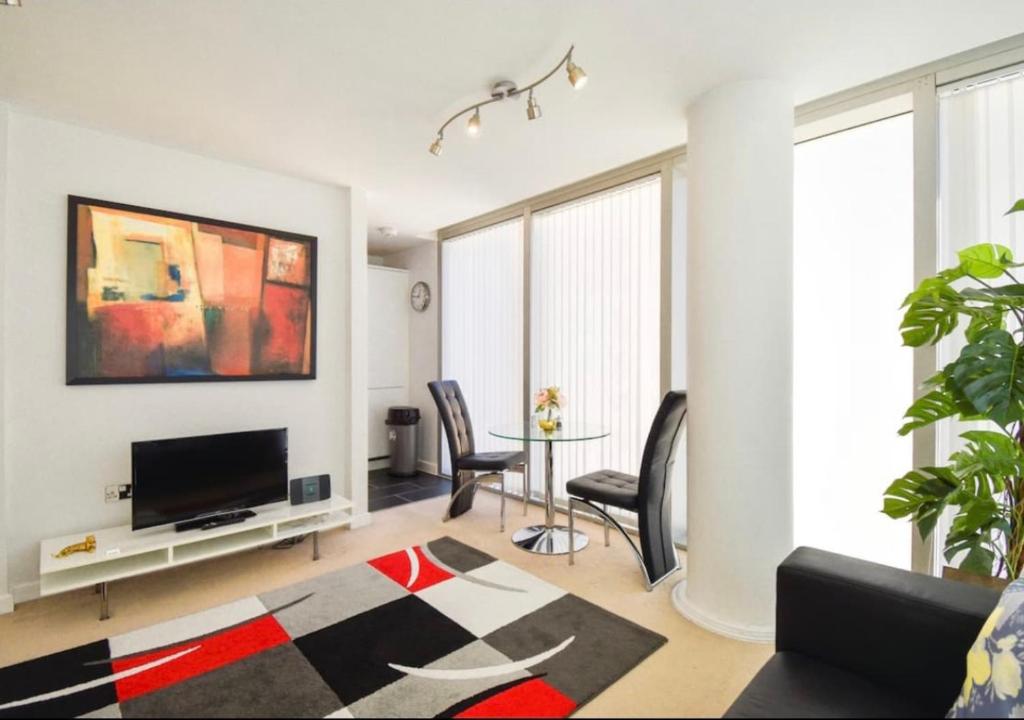 uma sala de estar com uma televisão e uma mesa com cadeiras em Central Hub Apartment with Balcony, Fast Wifi, Smart TV and Free Parking em Milton Keynes