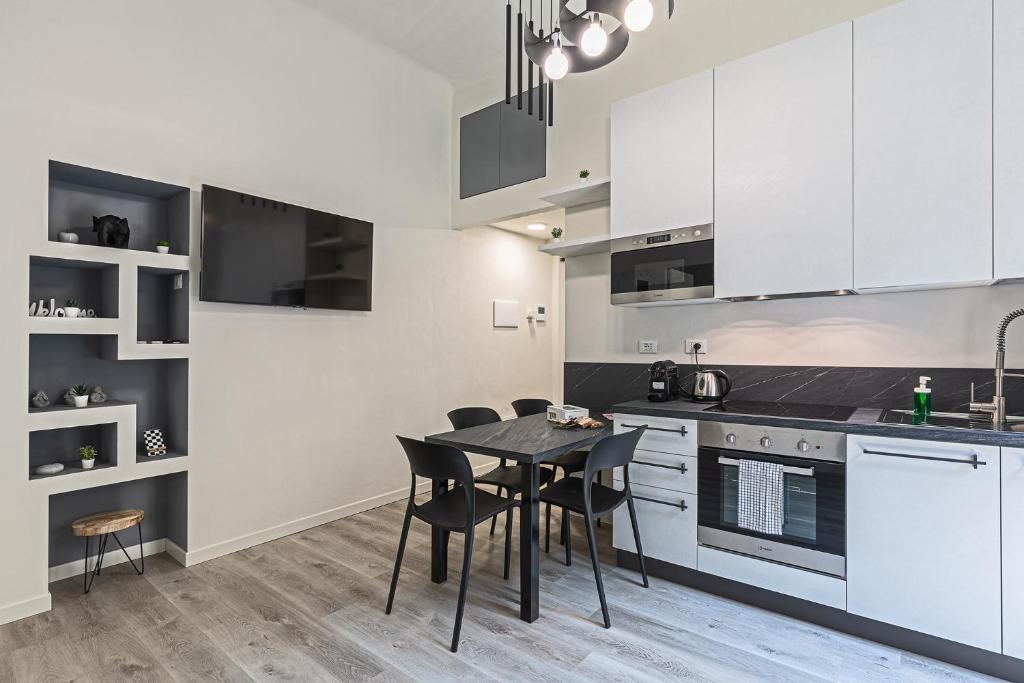 uma cozinha com armários brancos e uma mesa e cadeiras em La Boutique Milano: appartamento in Porta Romana em Milão