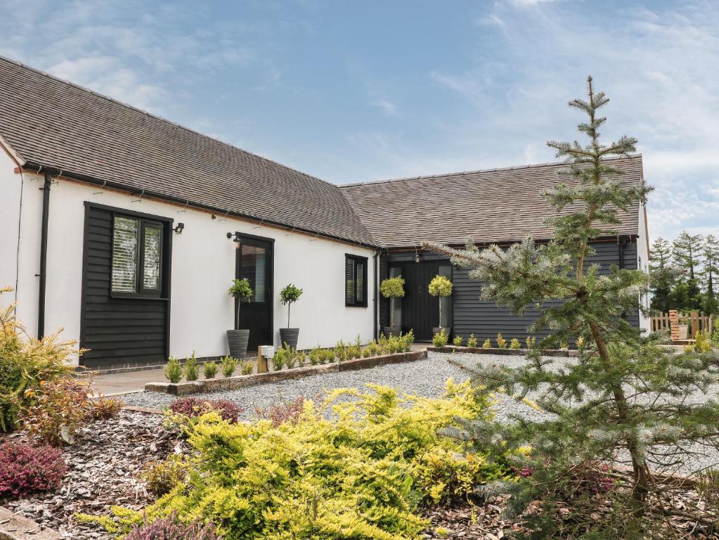 ein Haus mit schwarzen Rollläden und einem Garten in der Unterkunft The Den, Bank Top Farm in Ashbourne