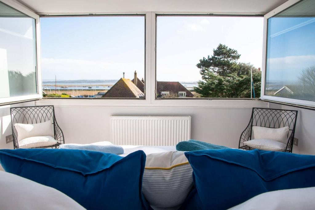 a room with a bed and two chairs and windows at Coastguard Cottage in Milford on Sea