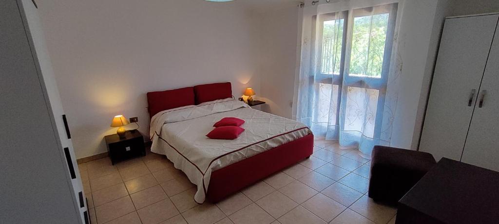 a bedroom with a red bed with two red pillows on it at Grazioso e confortevole attico, costa sud-ovest in Gonnesa