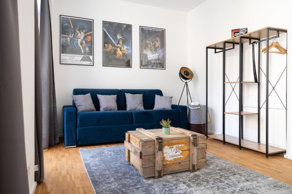 ein Wohnzimmer mit einem blauen Sofa und Bildern an der Wand in der Unterkunft Ko-Living - Gaming Suite am Alten Markt - Altstadt - 6P in Halle an der Saale