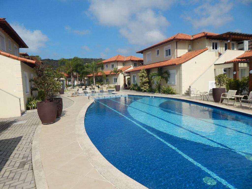 una piscina en un complejo con sillas en Linda e aconchegante casa a 400m da Praia de Geribá com Piscina - B35, en Búzios