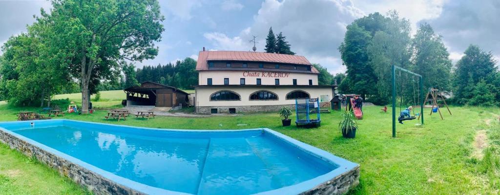 un bâtiment avec une piscine en face d'une aire de jeux dans l'établissement Chata Kačerov, 