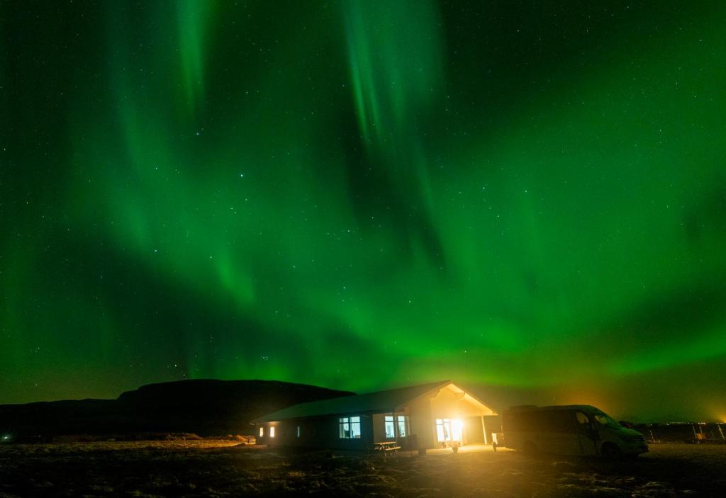 a cabin under the aurora in the sky at Álftröð Guesthouse in Brautarholt