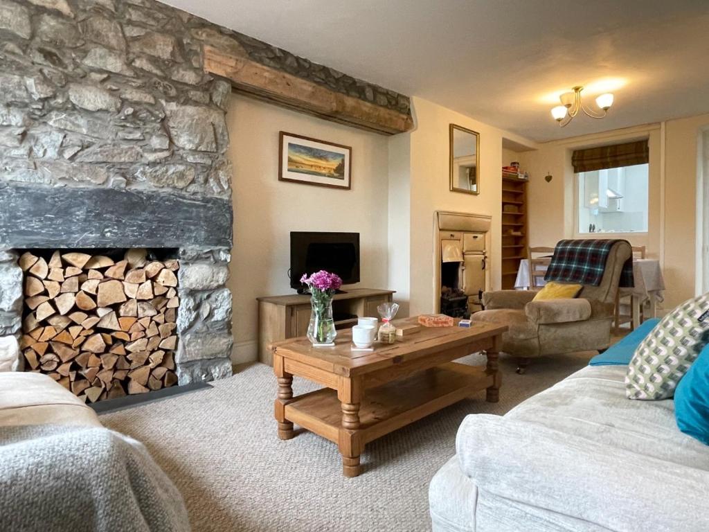 a living room with a stone fireplace and a table at Glasfryn Cottage Dolgellau in Dolgellau