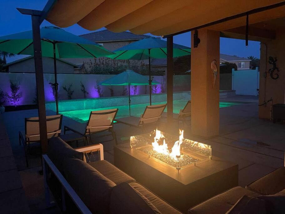 a fire pit in a patio with chairs and a pool at Desert Fantasy Oasis Pool, Jacuzzi, Royal Beds in Coachella