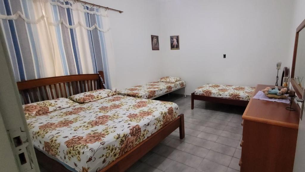 a bedroom with two beds and a dresser and a table at Aconchego Sagrada Face in Aparecida