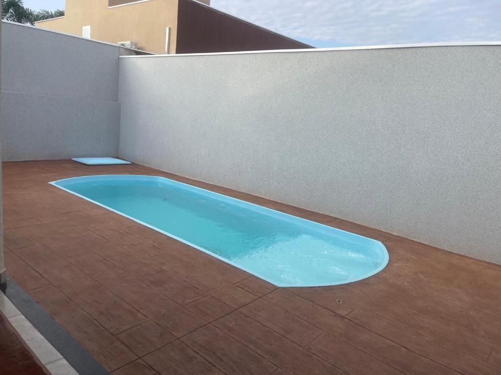 una piscina azul en la parte lateral de un edificio en Recanto Julia III, en Olímpia