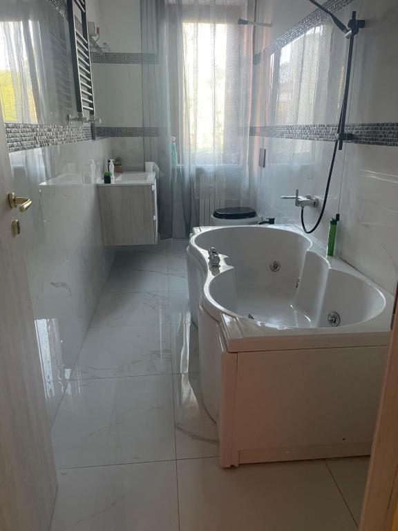 ein weißes Badezimmer mit einer Badewanne und einem Waschbecken in der Unterkunft Appartamento Mire&Geo in Voghera