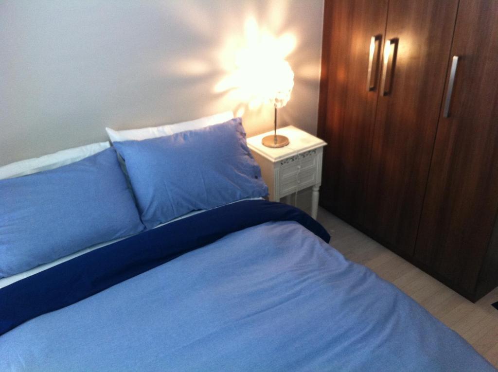 a bed with blue sheets and a lamp on a night stand at Beautiful apartment central location in Dublin