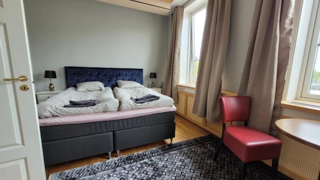 1 dormitorio con 1 cama y 1 silla roja en Mellanbrons B&B, en Åmål