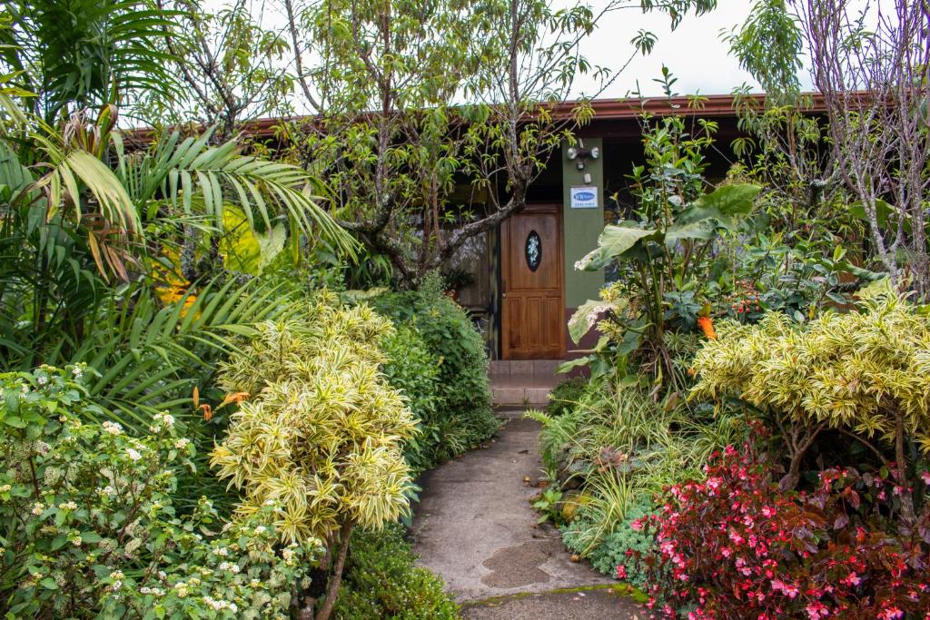 a garden entrance to a house with flowers at Cabinas las Manzanas Bed y Breakfast in El Copey