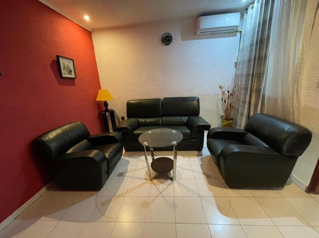 una sala de estar con 2 sofás de cuero y una mesa. en Homestay Studio, en Yaoundé