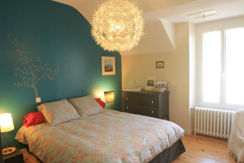 杜阿爾訥內的住宿－Chambre d'Hôte à Douarnenez，一间卧室配有一张大床和一个吊灯。