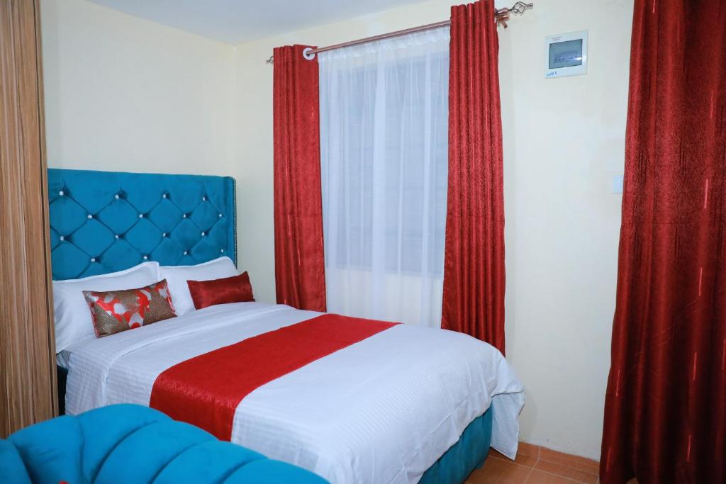a bedroom with a large bed with red curtains at Executive studio in Ruiru in Ruiru