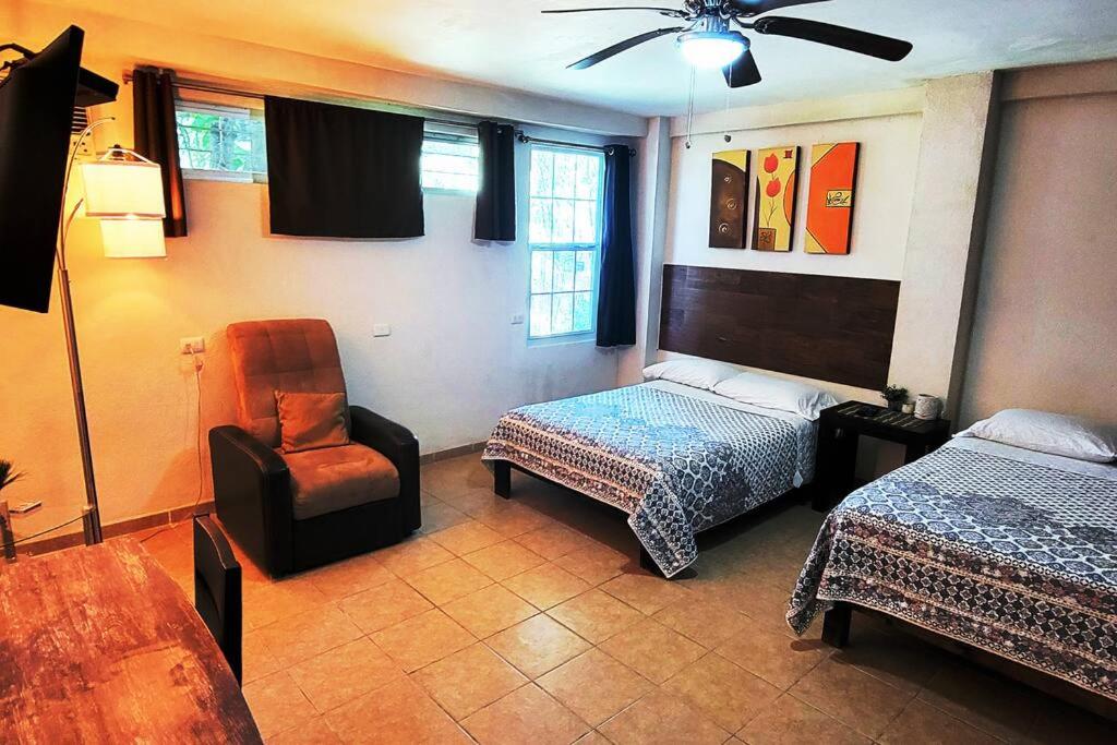 a bedroom with two beds and a chair and a ceiling fan at Departamento Comodo centrico Tv Ac wifi cocina parking, letra C in Ciudad Valles