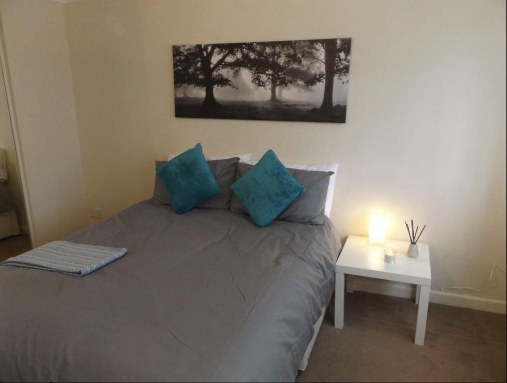 a bedroom with a bed with blue pillows and a table at Gainford House in Walsgrave on Sowe