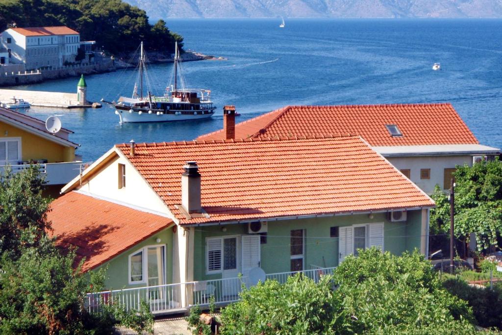 una casa con techo naranja y un barco en el agua en Apartments and rooms by the sea Jelsa, Hvar - 4602 en Jelsa