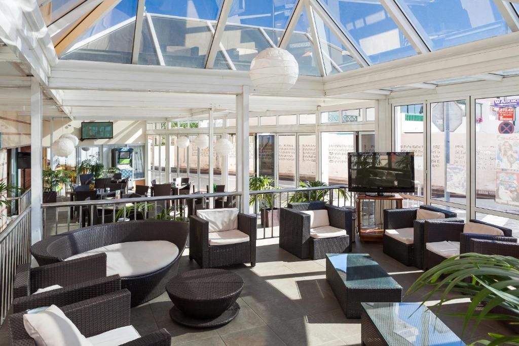 a large room with chairs and a television in a building at Aparthotel Los Dragos del Sur in Puerto de Santiago