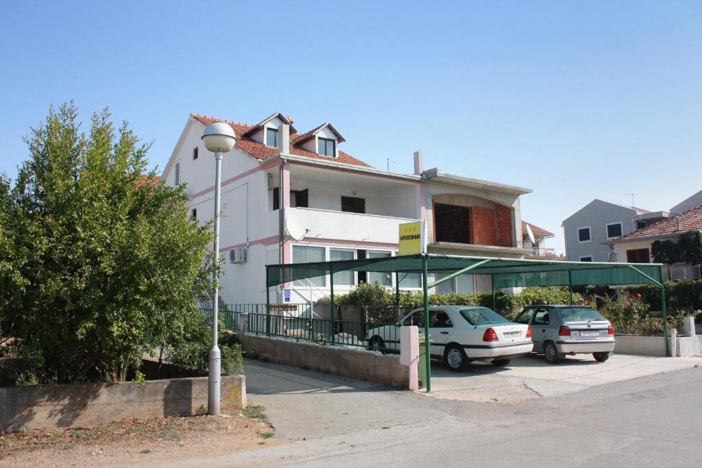 una casa blanca con coches aparcados en un estacionamiento en Apartments by the sea Stari Grad, Hvar - 5697, en Stari Grad