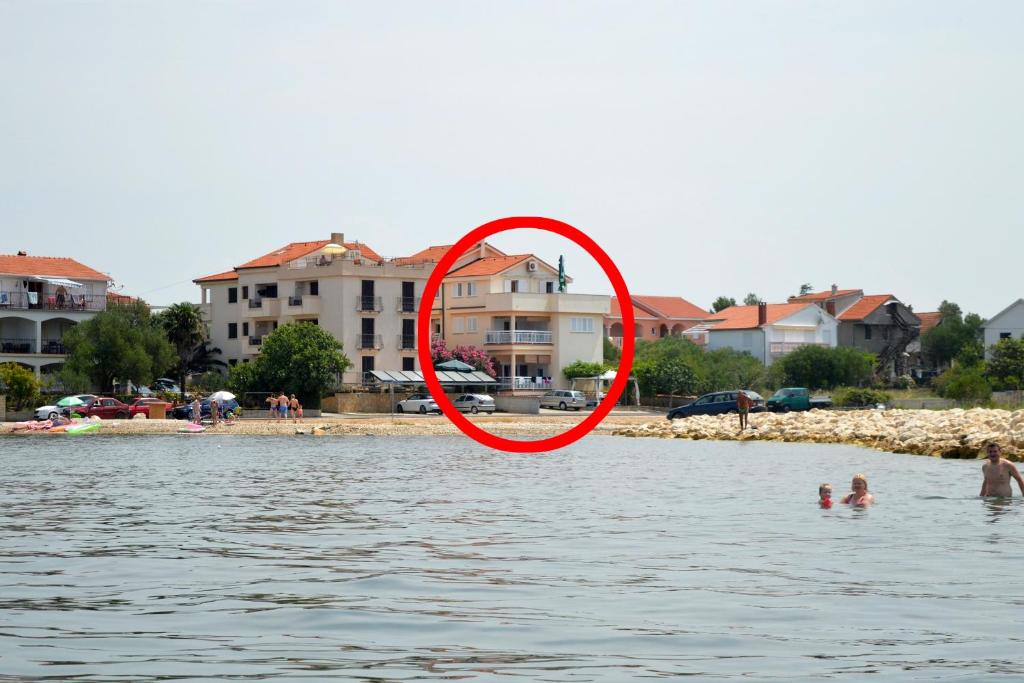 un cercle rouge dans l'eau près d'une plage dans l'établissement Apartments by the sea Sukosan, Zadar - 5864, à Sukošan