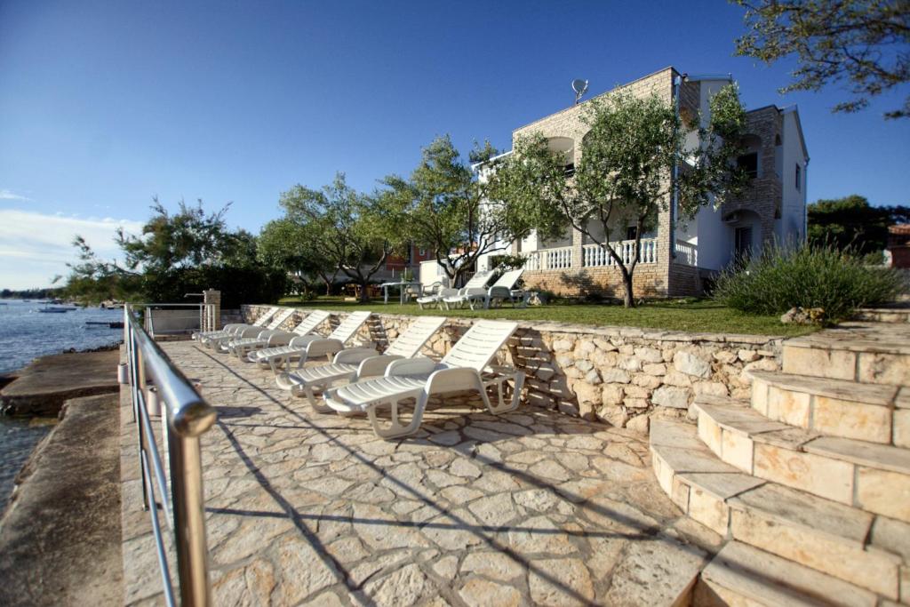 een rij ligstoelen naast het water bij Apartments by the sea Kozino, Zadar - 5803 in Kožino