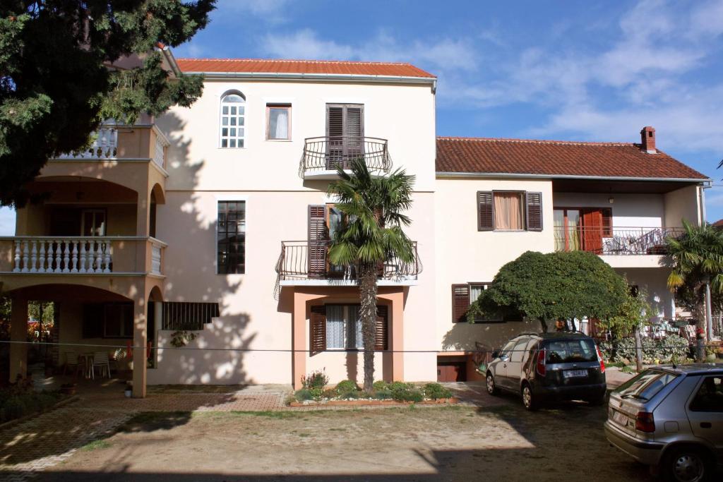 une maison blanche avec un palmier en face dans l'établissement Apartments with a parking space Biograd na Moru, Biograd - 5899, à Biograd na Moru
